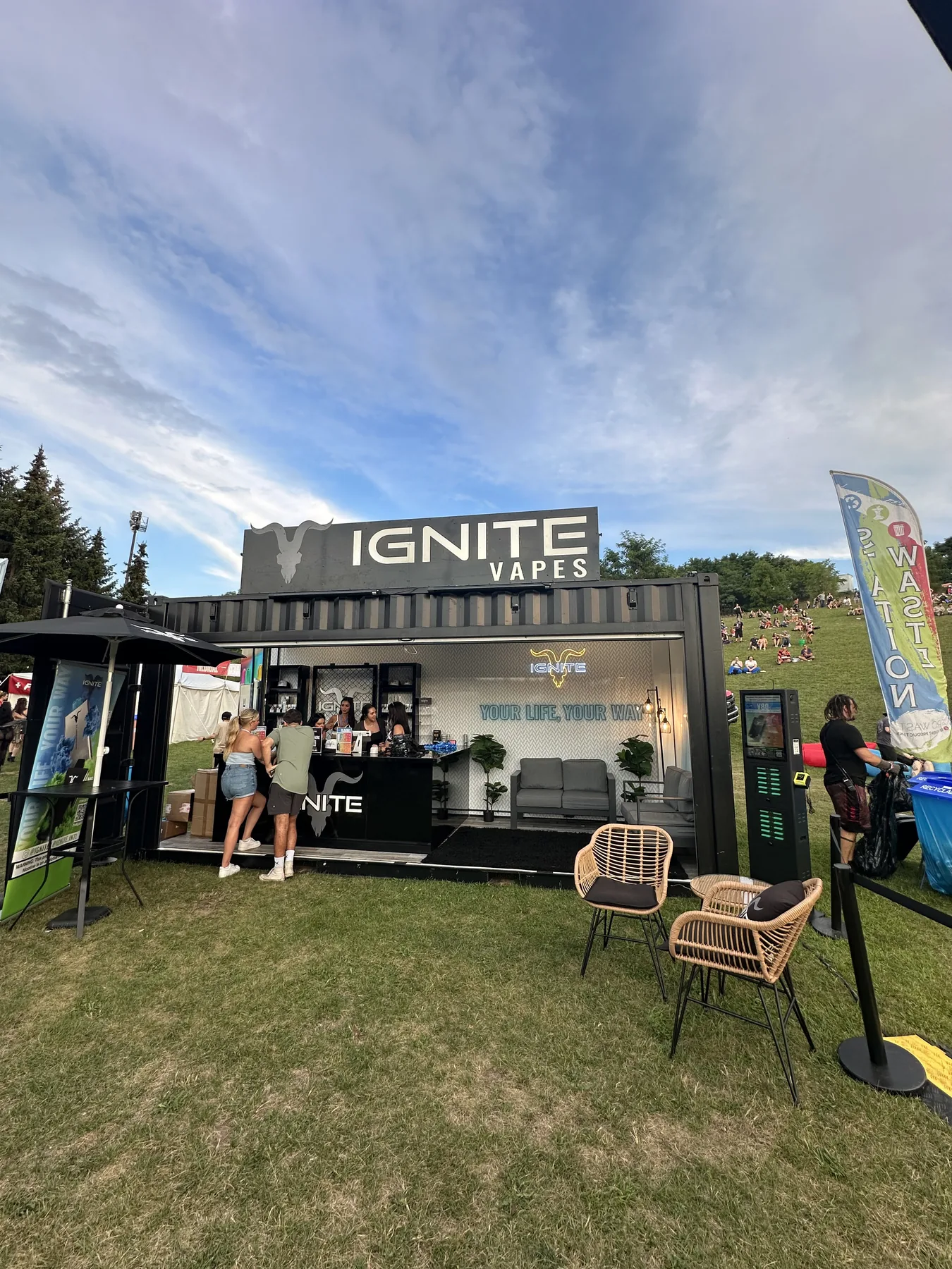 IGNITE Vapes stand at a festival: black container with counter and lounge on a lawn