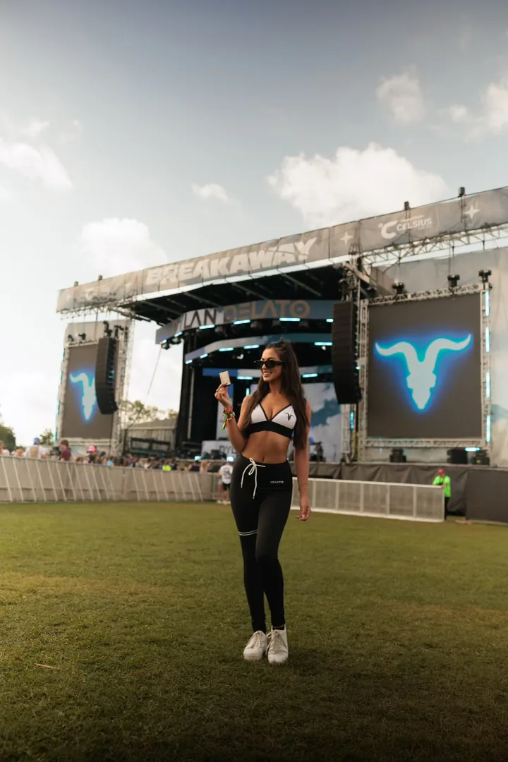 Woman in IGNITE sportswear in front of a festival stage with a glowing IGNITE skull on the screens