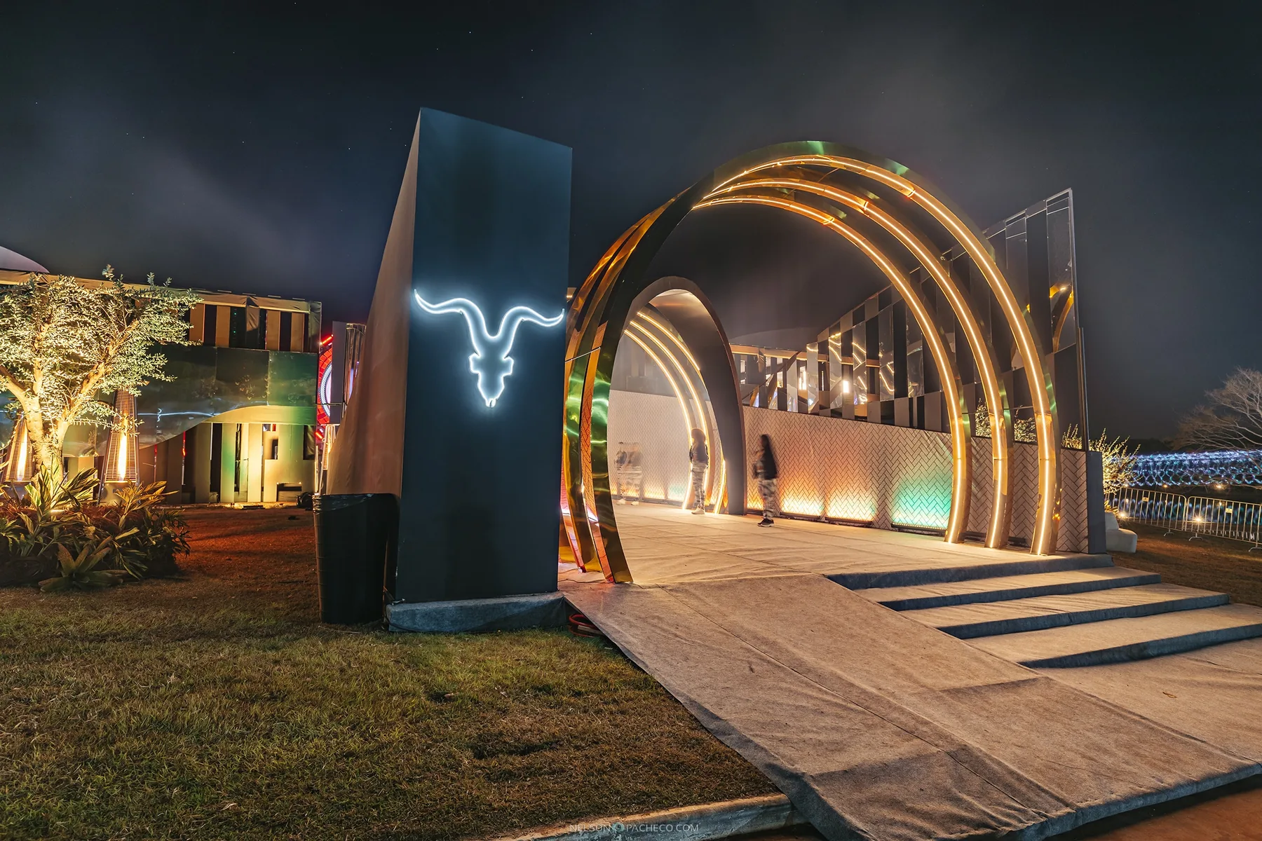 Entrance to an IGNITE event at night with a glowing skull and light arches